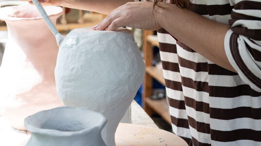 vrouw glazuurt een theepot in haar atelier